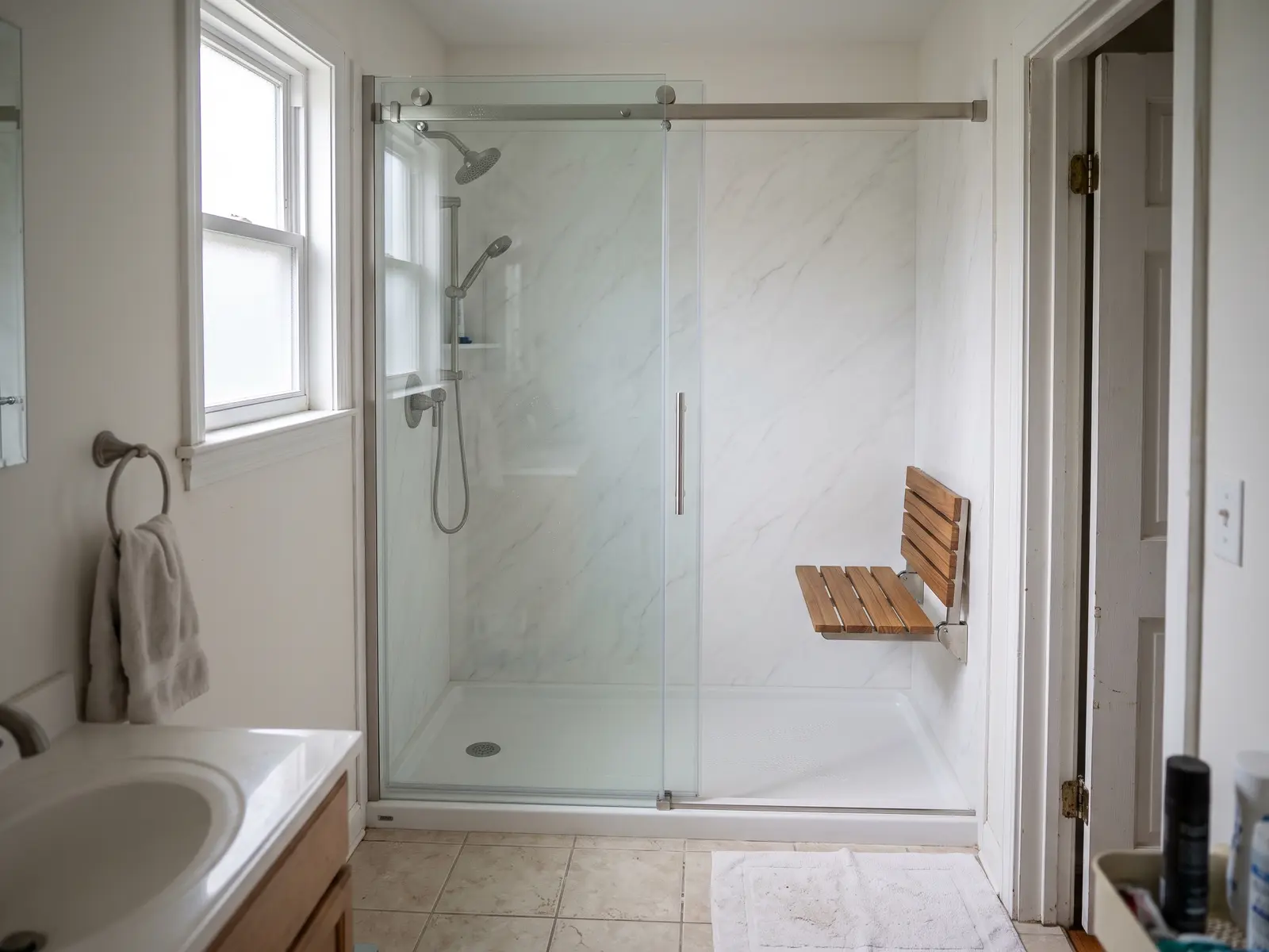 Former tub alcove in a Lexington, KY ranch bathroom rebuilt as a walk-in shower with white panel walls and a sliding glass door